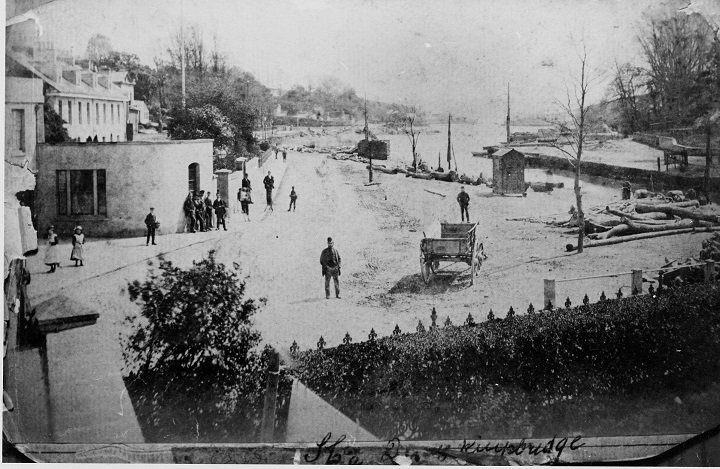 At the head of Kingsbridge estuary looking south from Ryeford House.   
A cart in road, logs lying all around estuary banks.