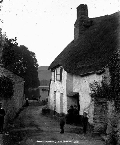 'Shadycombe, Salcombe. No. 221'. View down lane, past cottages and across the estuary. Small boys on porch, other bystanders. '
