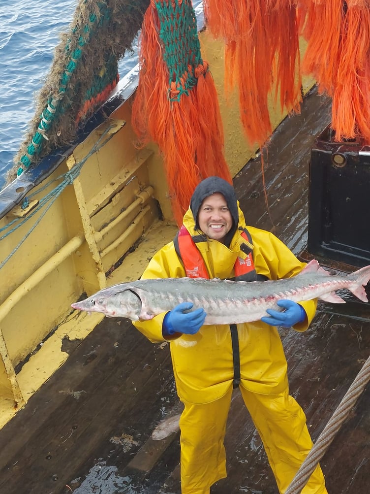 Sean Beck posing with the sturgeon he caught shortly before it was released back into the sea