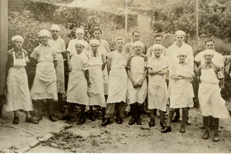 Milking class from Harry Rogers' farm at the bottom of Duncombe Street, Kingsbridge. Group of boys dressed in white aprons and caps, with numbered armbands.