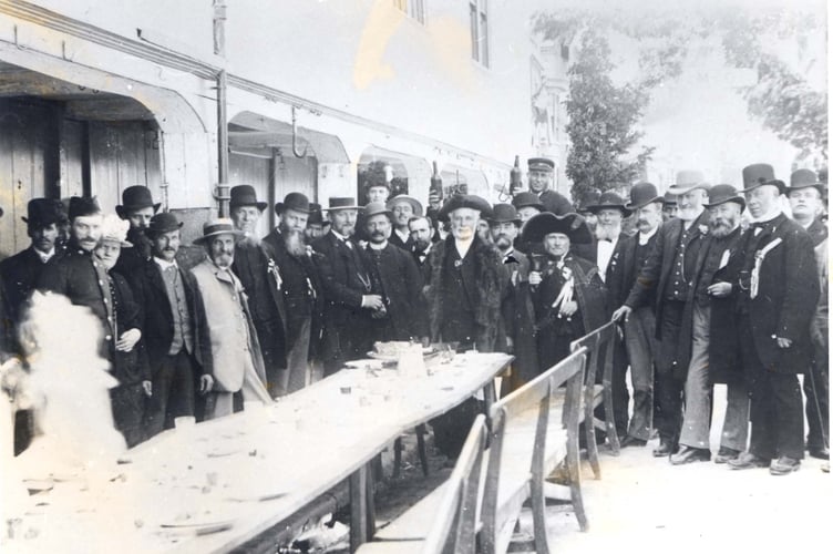 1887 Queen Victoria’s Jubilee celebration outside the Shambles, Fore Street, Kingsbridge. Town Crier and mayor present. Other gentlemen assembled round a long table.  