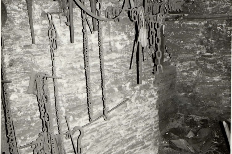 Corner view of Stokenham forge showing chains, rods etc. hanging on wall
