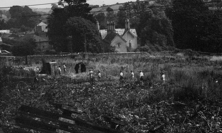 Group of people looking at an allotment plot. Possibly inspecting bomb damage during WWII. 