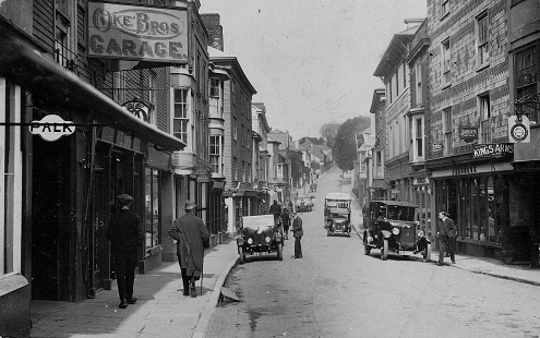 1920 (circa) view up Fore Street, Kingsbridge. Shows Oke Bros Garage on left and Kings Arms on the right, cars and people in the street.